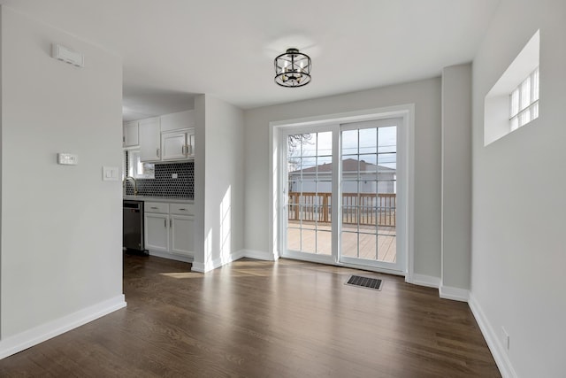 unfurnished dining area with baseboards, visible vents, and dark wood-type flooring