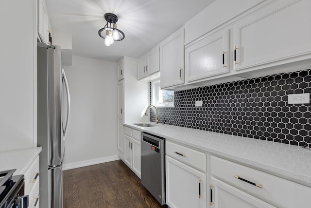 kitchen featuring stainless steel appliances, tasteful backsplash, dark wood-type flooring, white cabinetry, and a sink