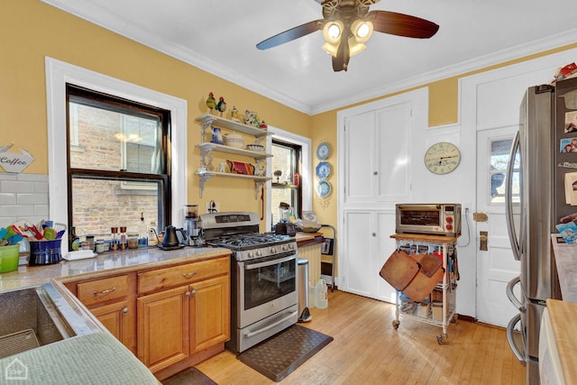 kitchen with a toaster, light wood finished floors, stainless steel appliances, light countertops, and ornamental molding