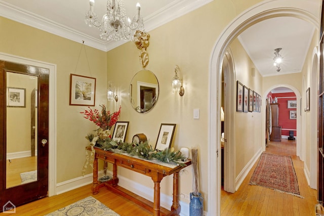 hall with hardwood / wood-style flooring, baseboards, arched walkways, and crown molding