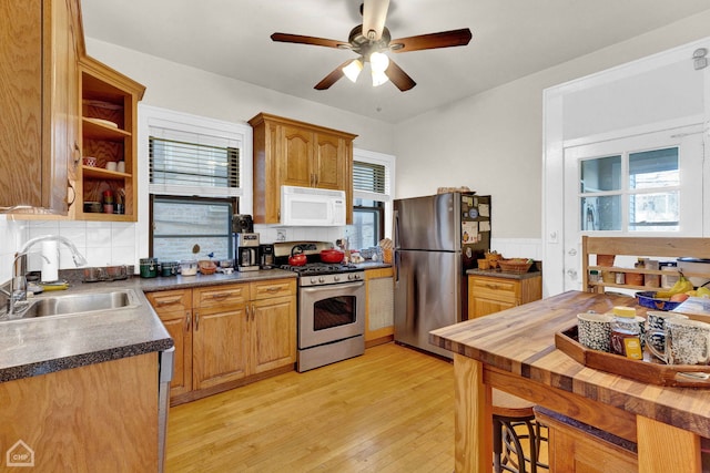 kitchen with a sink, wood counters, appliances with stainless steel finishes, open shelves, and light wood finished floors