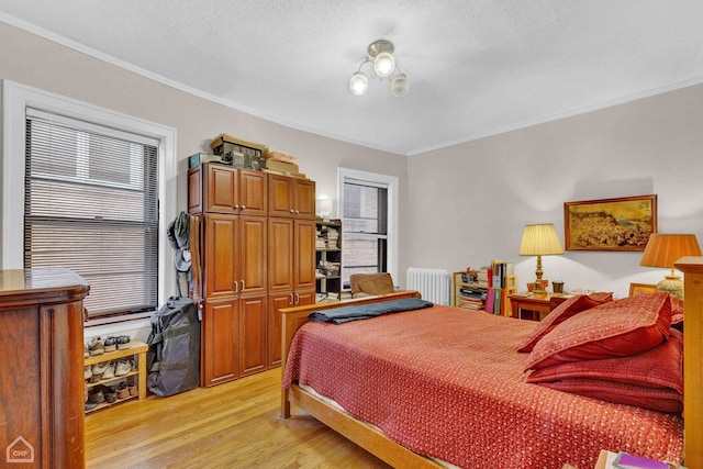 bedroom with crown molding, light wood-style floors, a textured ceiling, and radiator