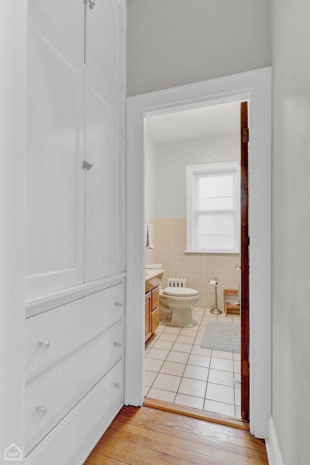 bathroom featuring toilet, a wainscoted wall, vanity, tile walls, and hardwood / wood-style floors