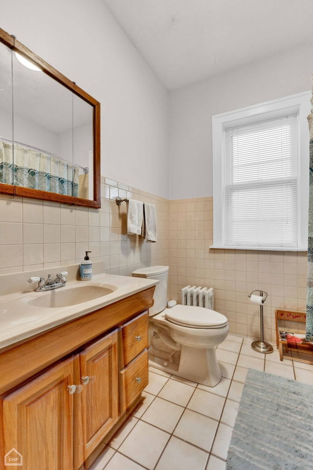 full bathroom with tile patterned flooring, toilet, vanity, tile walls, and radiator heating unit