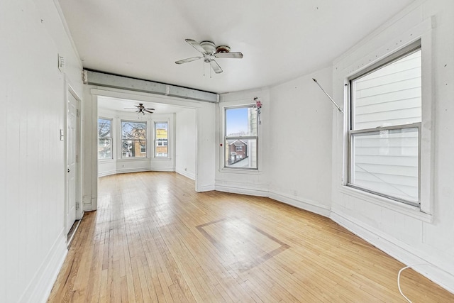 spare room with a ceiling fan, light wood-style flooring, and baseboards