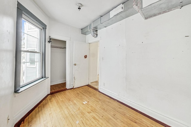 unfurnished bedroom featuring a closet, wood finished floors, and baseboards