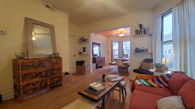 living room featuring visible vents, wood finished floors, and ornamental molding