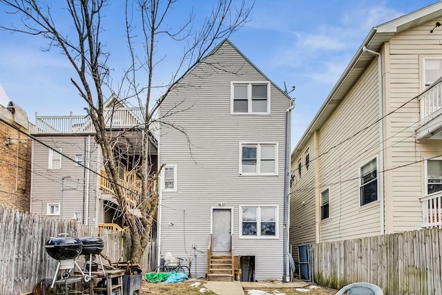 rear view of house with entry steps and a fenced backyard