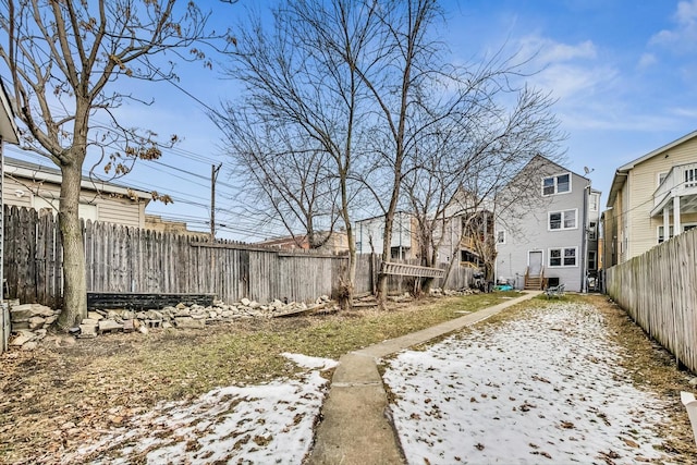 snowy yard with a residential view and fence