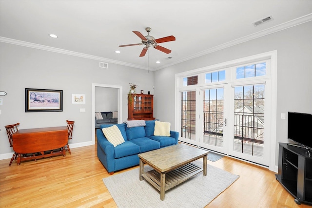 living room with crown molding, light wood-type flooring, visible vents, and baseboards