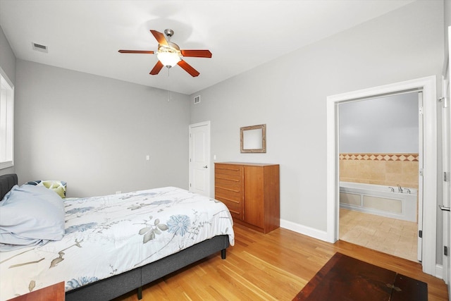 bedroom with light wood finished floors, baseboards, visible vents, and ensuite bathroom