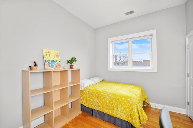 bedroom featuring visible vents, baseboards, and wood finished floors