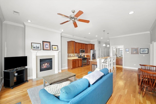 living room with light wood finished floors, baseboards, visible vents, and ceiling fan