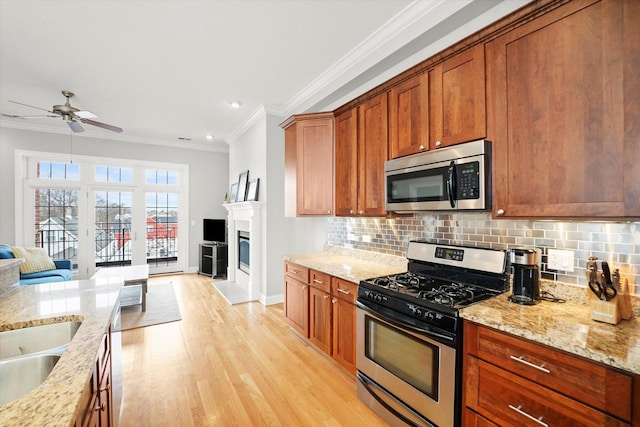 kitchen with light wood finished floors, stainless steel appliances, tasteful backsplash, and crown molding