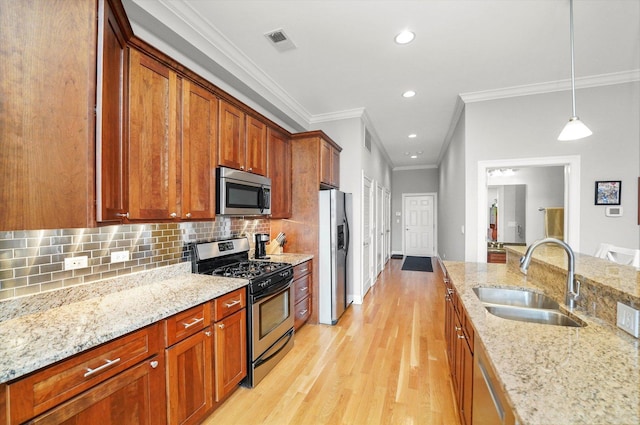 kitchen featuring visible vents, a sink, stainless steel appliances, light wood-style floors, and backsplash