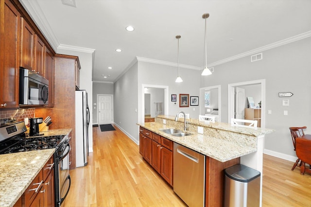 kitchen featuring light wood finished floors, stainless steel appliances, visible vents, backsplash, and a sink