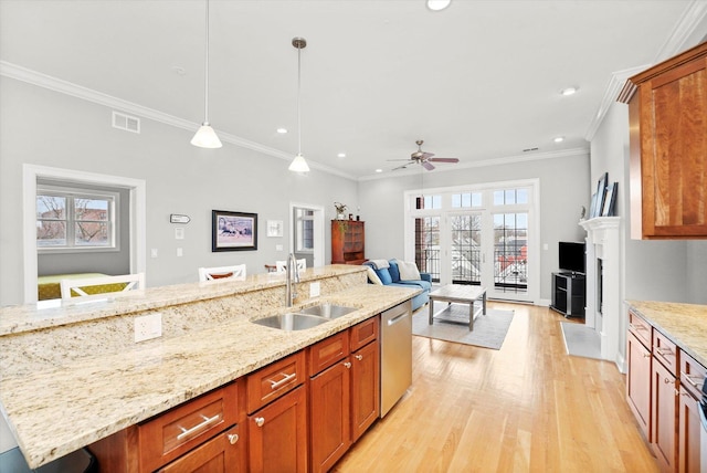 kitchen with light wood finished floors, visible vents, decorative light fixtures, a sink, and stainless steel dishwasher