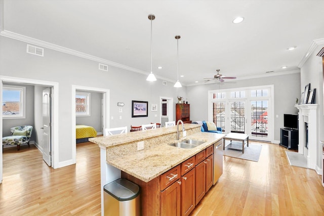 kitchen featuring visible vents, a fireplace with flush hearth, a sink, light wood-type flooring, and dishwasher