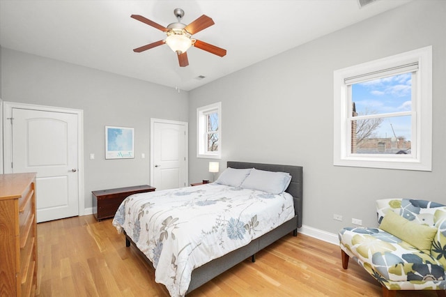 bedroom with light wood finished floors, a ceiling fan, and baseboards