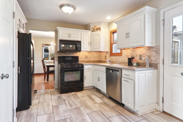 kitchen featuring white cabinetry, black appliances, light countertops, and backsplash