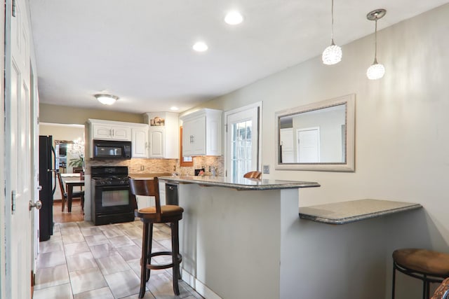 kitchen with black appliances, white cabinetry, a kitchen breakfast bar, and pendant lighting