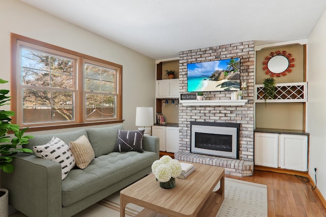 living area with a brick fireplace and light wood-type flooring