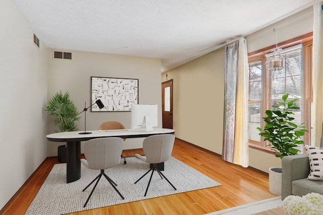 office area with light wood finished floors and visible vents