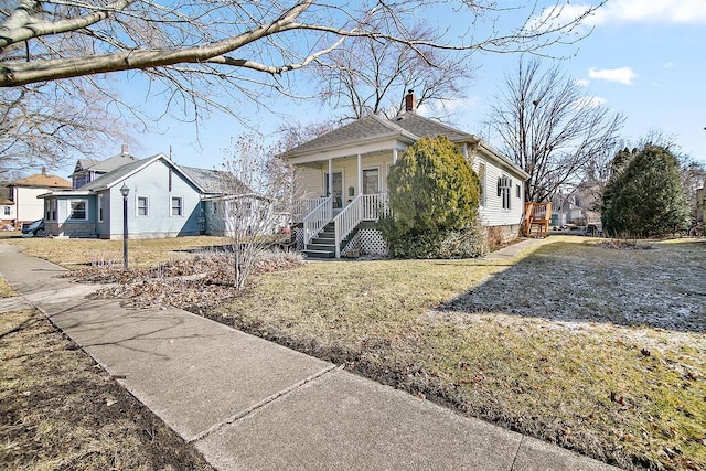 view of front of home featuring a front yard, covered porch, and a chimney