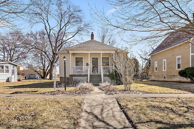 view of front of home featuring covered porch, roof with shingles, and a chimney