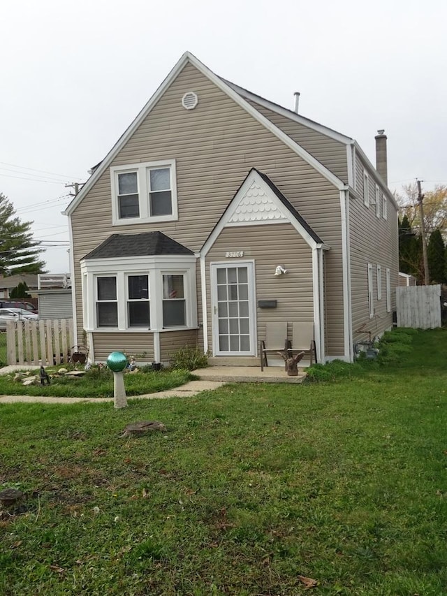 rear view of property with fence and a lawn