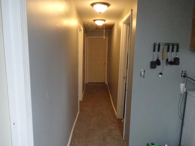 hallway featuring attic access, light colored carpet, and baseboards