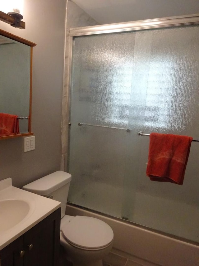 full bathroom featuring combined bath / shower with glass door, vanity, toilet, and tile patterned floors