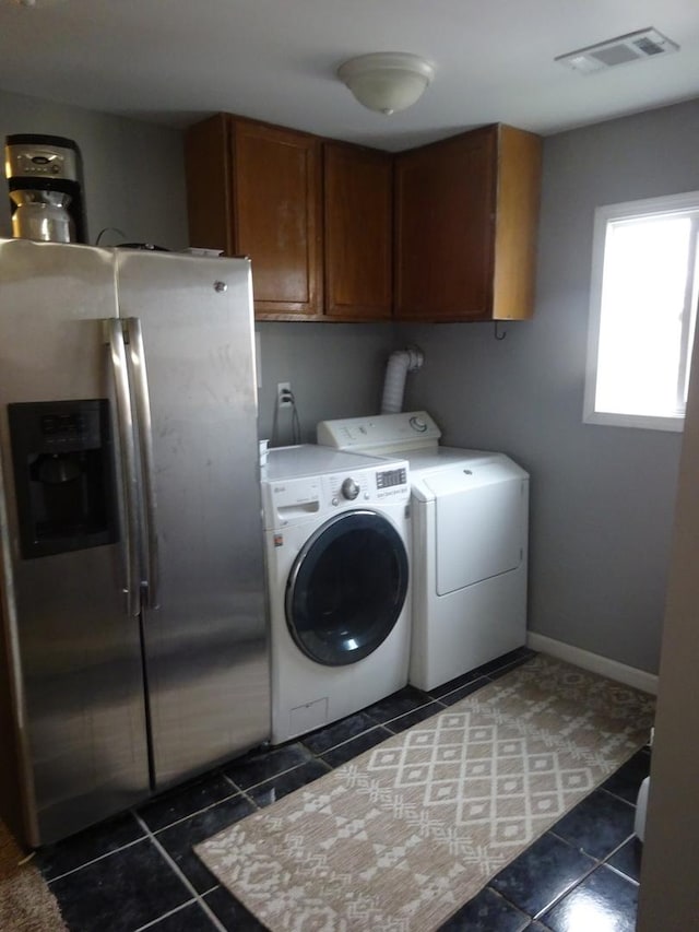 laundry room with visible vents, separate washer and dryer, dark tile patterned floors, and cabinet space