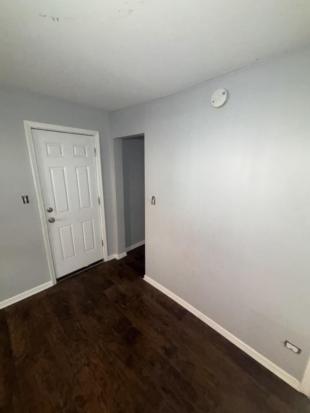 empty room featuring baseboards and dark wood finished floors