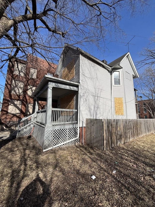 view of side of home with a porch and fence