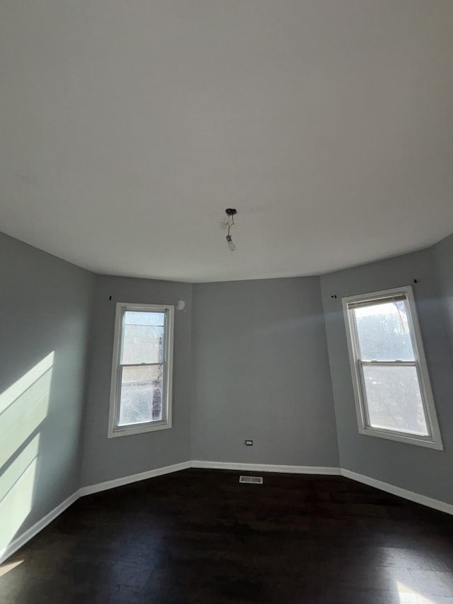 empty room with dark wood-style flooring and baseboards