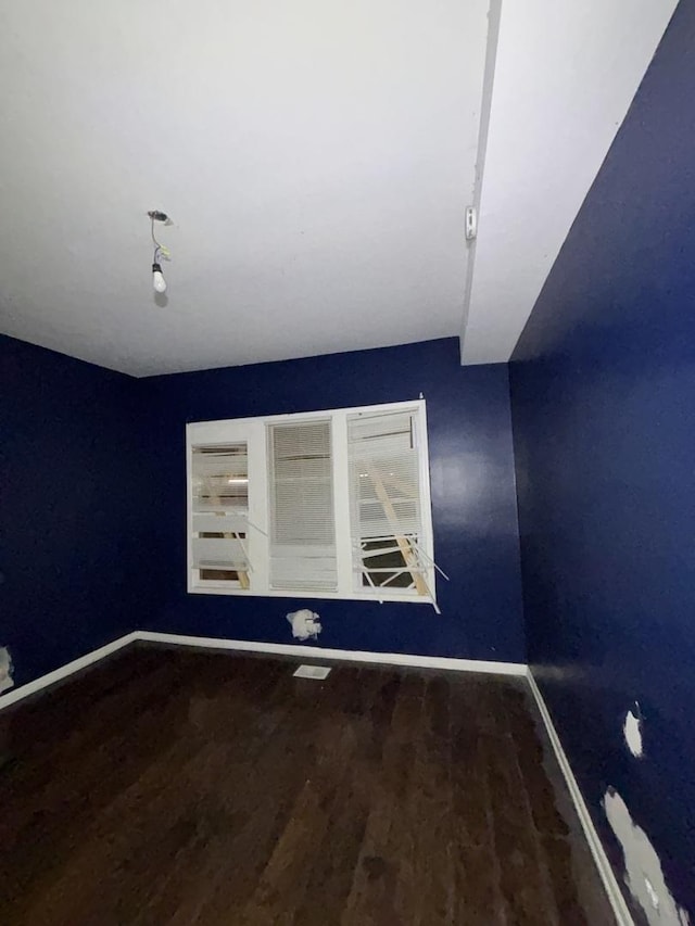 spare room featuring baseboards and wood finished floors