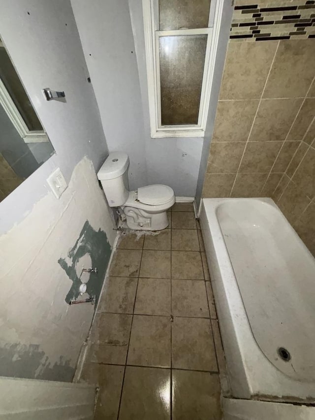 full bath featuring tile patterned flooring, toilet, and a bath