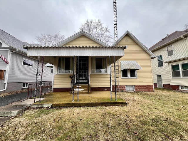 rear view of house featuring covered porch and a yard