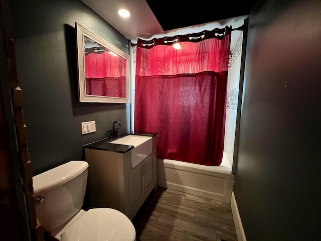 bathroom with toilet, wood finish floors, vanity, baseboards, and shower / bath combo with shower curtain