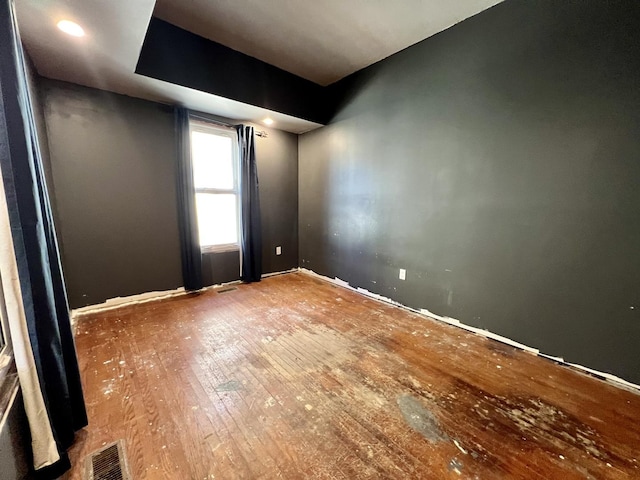 empty room featuring visible vents and hardwood / wood-style flooring