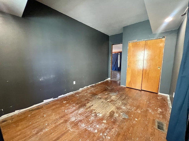 unfurnished bedroom with a closet, visible vents, and wood finished floors