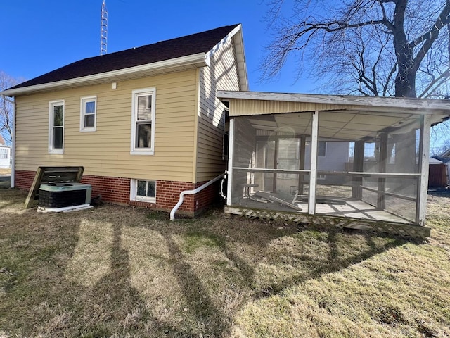 rear view of house featuring a sunroom, central AC, and a yard