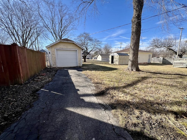 view of yard featuring a garage, an outdoor structure, driveway, and fence