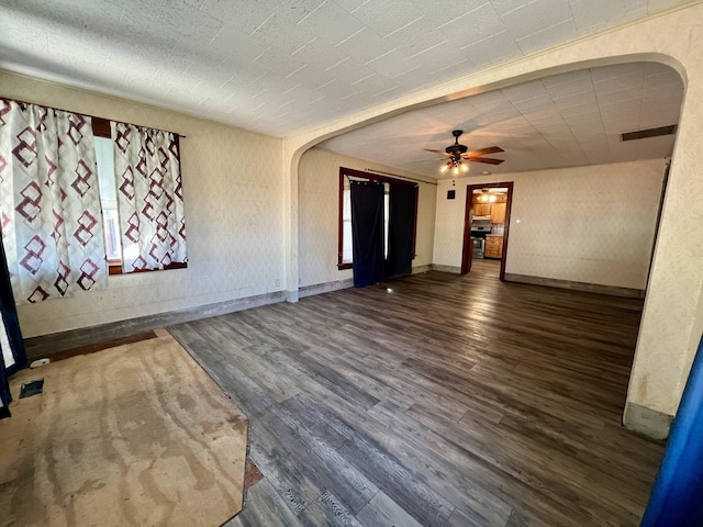 spare room featuring arched walkways, ceiling fan, wood finished floors, visible vents, and baseboards