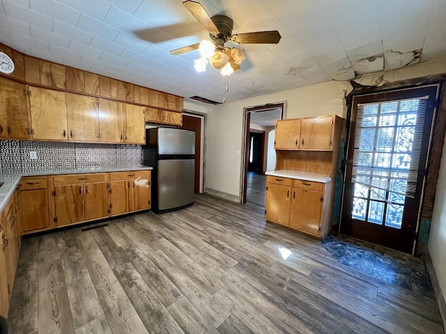 kitchen featuring freestanding refrigerator, light countertops, backsplash, and wood finished floors