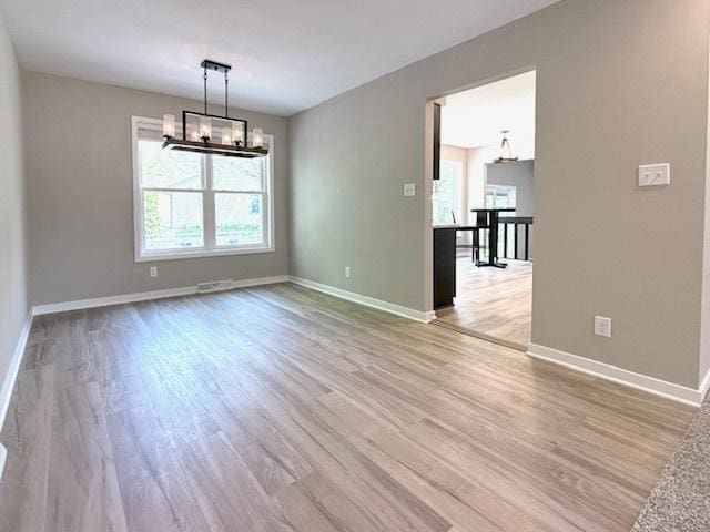 1816 Sadler Dr, Champaign, IL 61821 - unfurnished room featuring healthy amount of natural light, a chandelier, and light wood-type flooring