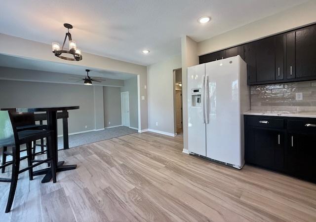 1816 Sadler Dr, Champaign, IL 61821 - kitchen with white refrigerator with ice dispenser, dark cabinetry, ceiling fan, decorative light fixtures, and light countertops