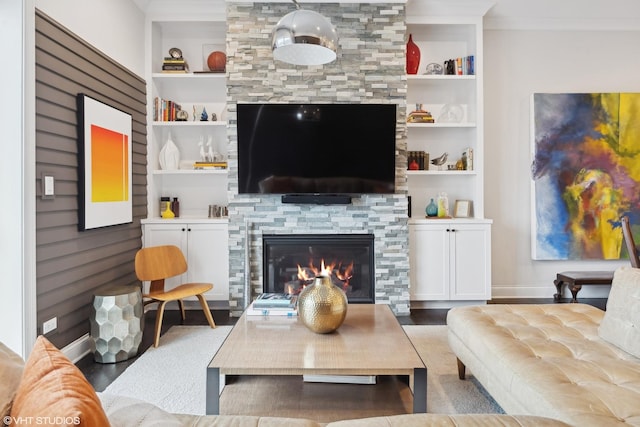 living room with built in shelves, crown molding, a large fireplace, wood finished floors, and baseboards