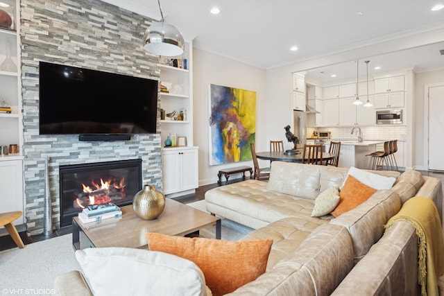 living area with recessed lighting, a fireplace, crown molding, and wood finished floors